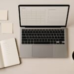Notebook, sticky notes, and a laptop showing a content calendar and SEO checklist on a desk